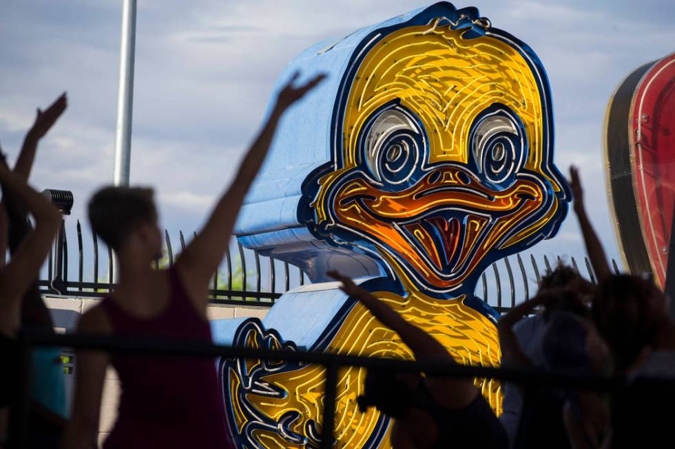 People participate in a hot yoga session in the outdoor Neon Boneyard area at the Neon Museum i ...