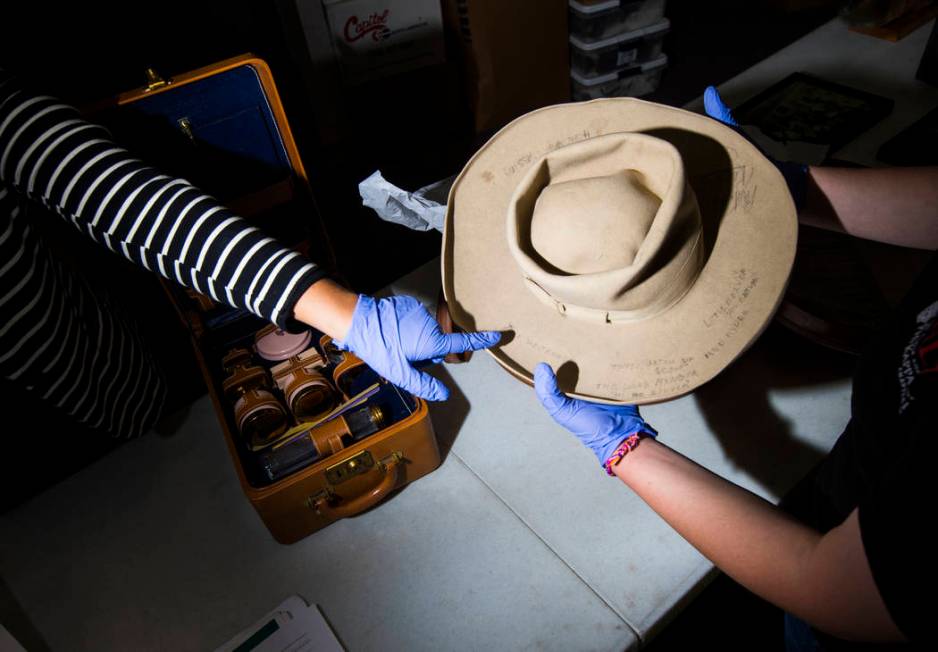 Doctoral student Paige Figanbaum, left, points to a cowboy hat with written markings referencin ...