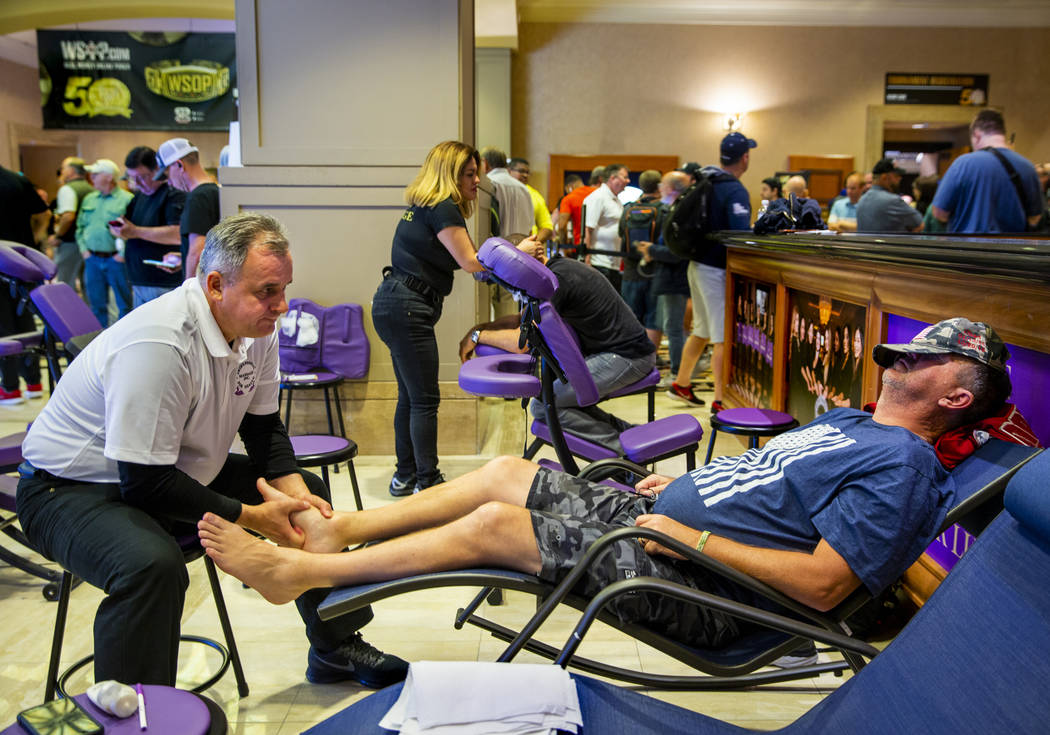 Mirek Rurka with Professional Massage Inc., works the feet of poker player Darren Hicks, of Cor ...