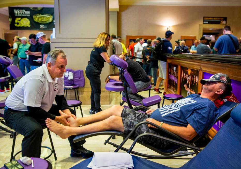 Mirek Rurka with Professional Massage Inc., works the feet of poker player Darren Hicks, of Cor ...