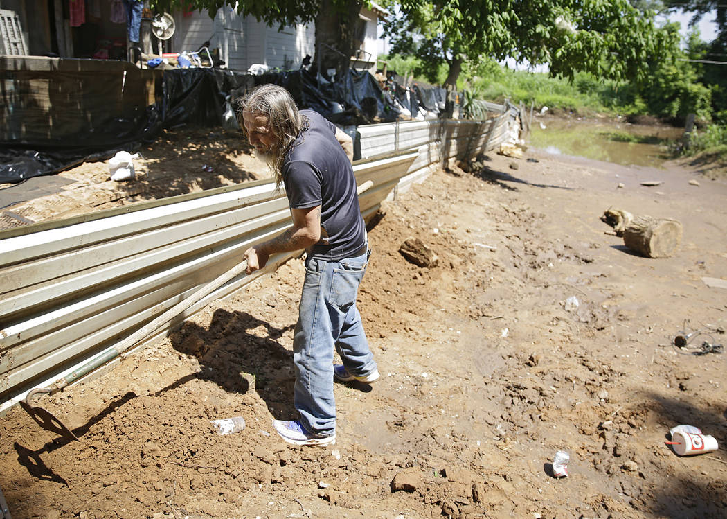 Billy Madison dismantles a homemade levee behind his home in the Garden City neighborhood in we ...