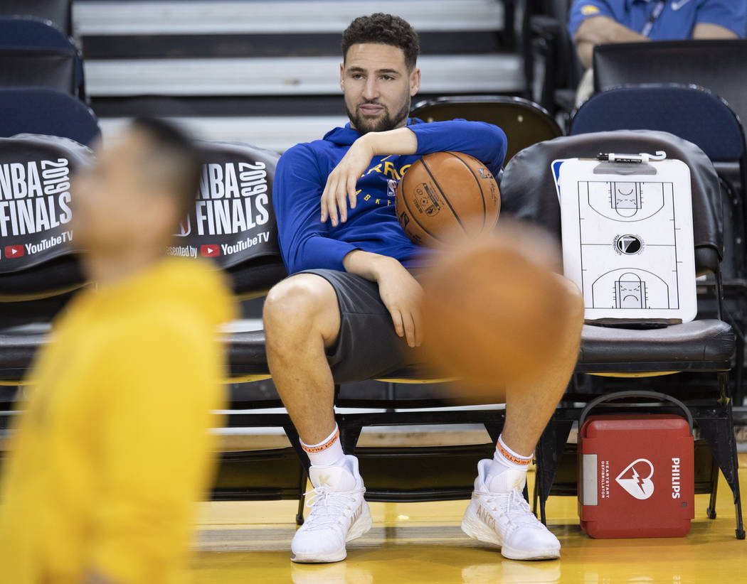 Golden State Warriors' Klay Thompson sits on the bench watching teammates during practice for t ...