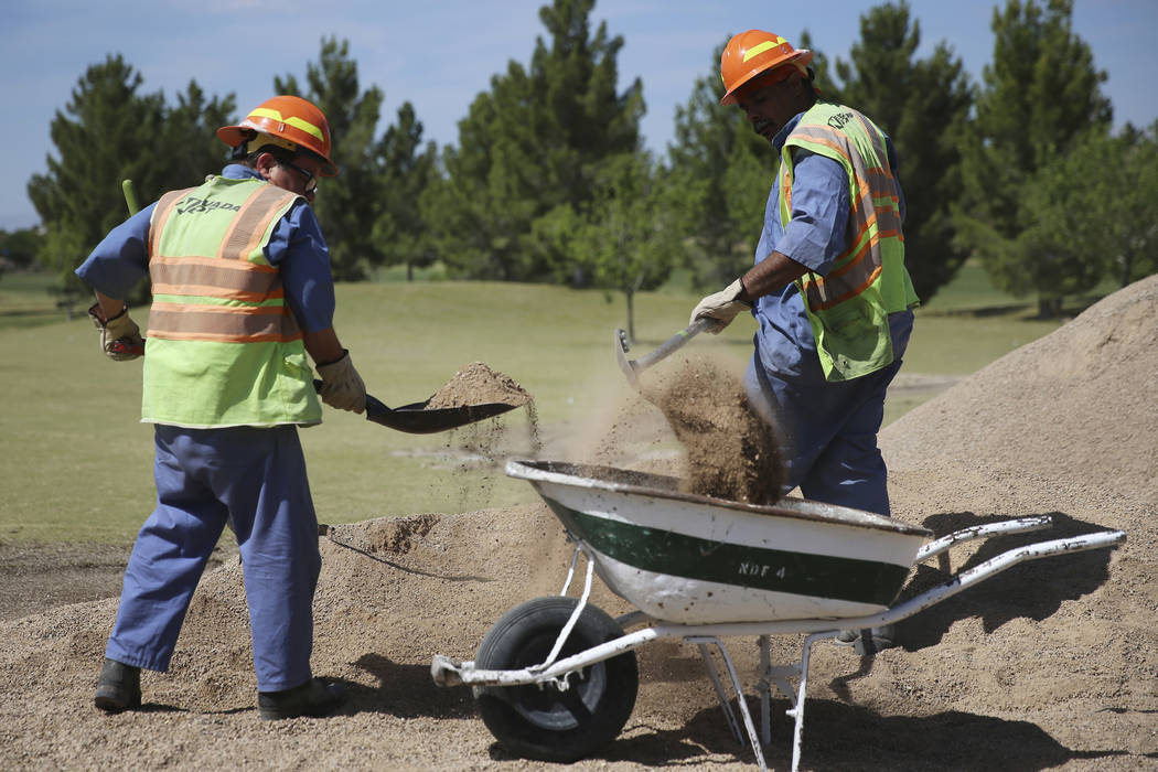 Peter Ruiz, left, and Benjamin Holly, members of the Nevada Division of Forestry, pick up dirt ...
