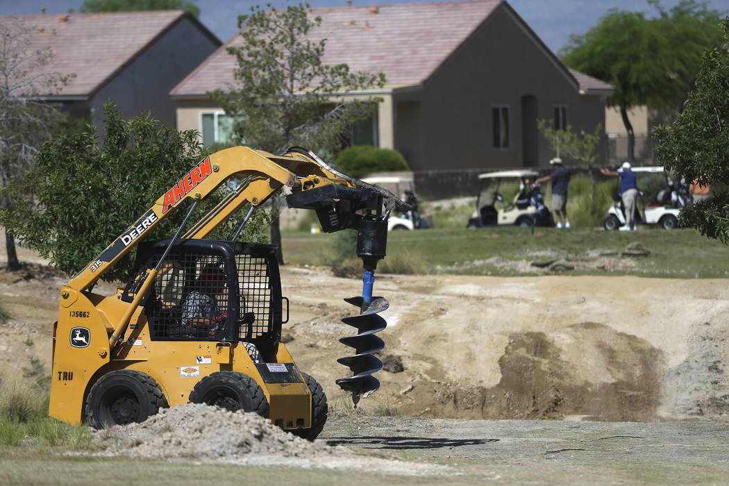 Golfers play in the background as a workers digs a hole at the Aliante Golf Club in North Las V ...