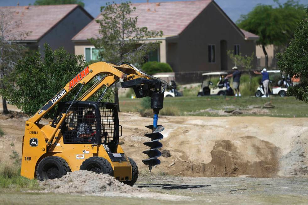 Golfers play in the background as a workers digs a hole at the Aliante Golf Club in North Las V ...