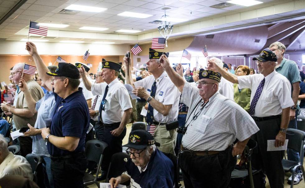 Veterans raise their flags as "God Bless the USA" is sung during a ceremony commemora ...