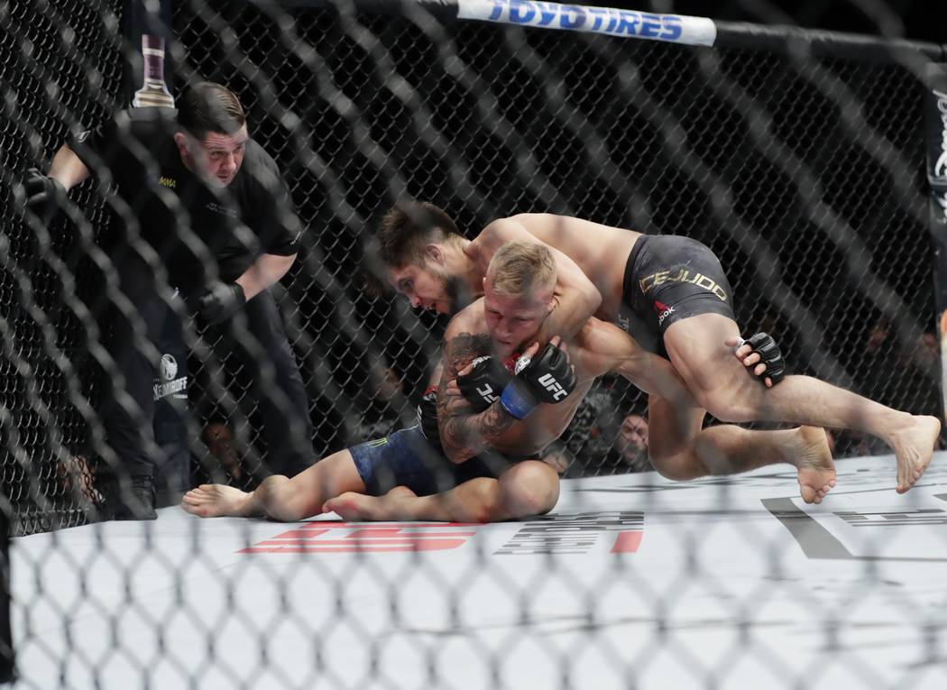 Henry Cejudo, right, wrestles with TJ Dillashaw during the first round of a flyweight mixed mar ...