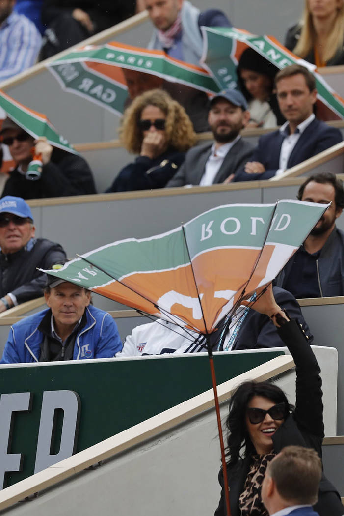 A spectator battles with her umbrella after the wind inverted it during the semifinal match of ...