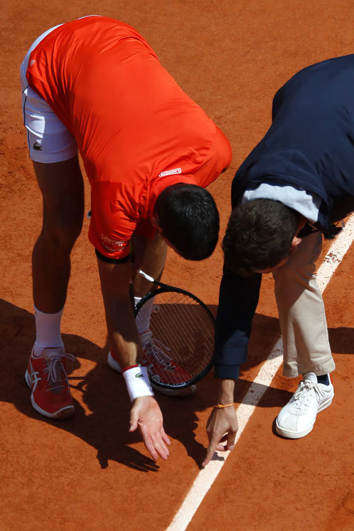 Serbia's Novak Djokovic, left, discusses a ball mark with the referee as he plays against Austr ...