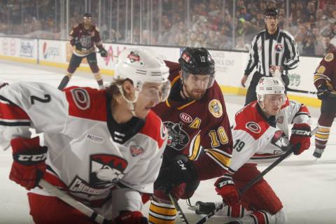 Chicago Wolves left wing Curtis McKenzie (10) is squeezed by Charlotte Checkers' Jake Bean (2) ...