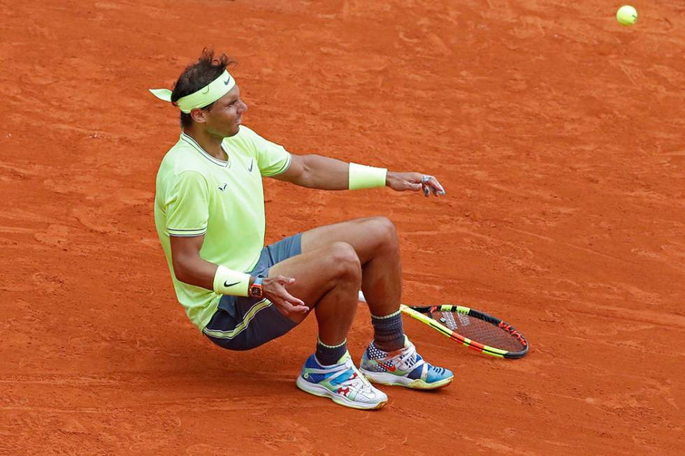 Spain's Rafael Nadal falls to the ground as the return goes out, to celebrates his record 12th ...