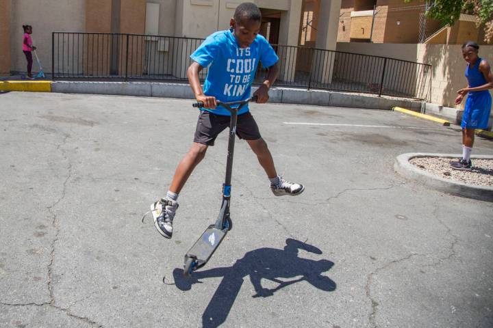 Devon Brown, 9, of North Las Vegas does a trick on his scooter during a summer day at Nellis Su ...