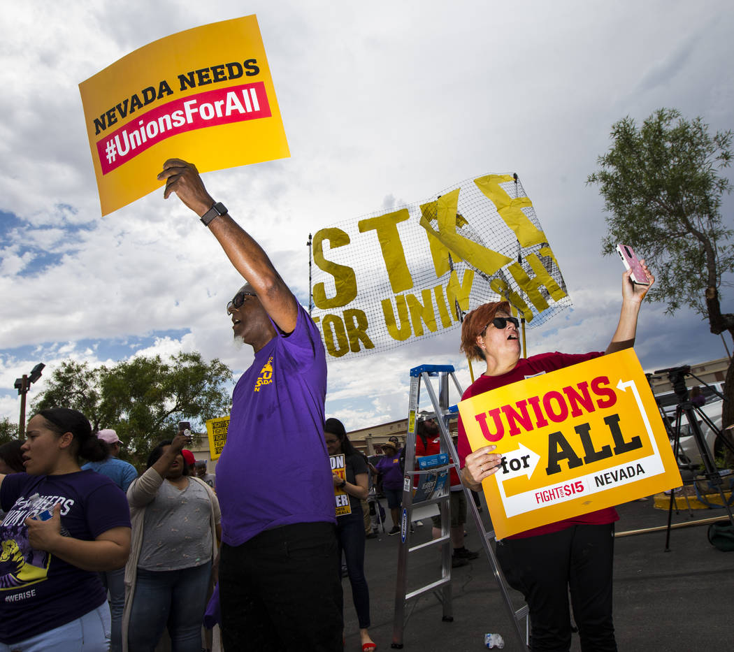 Michael Collins, left, and Lupe Guzman, both of Las Vegas, hold up signs while protesting in su ...