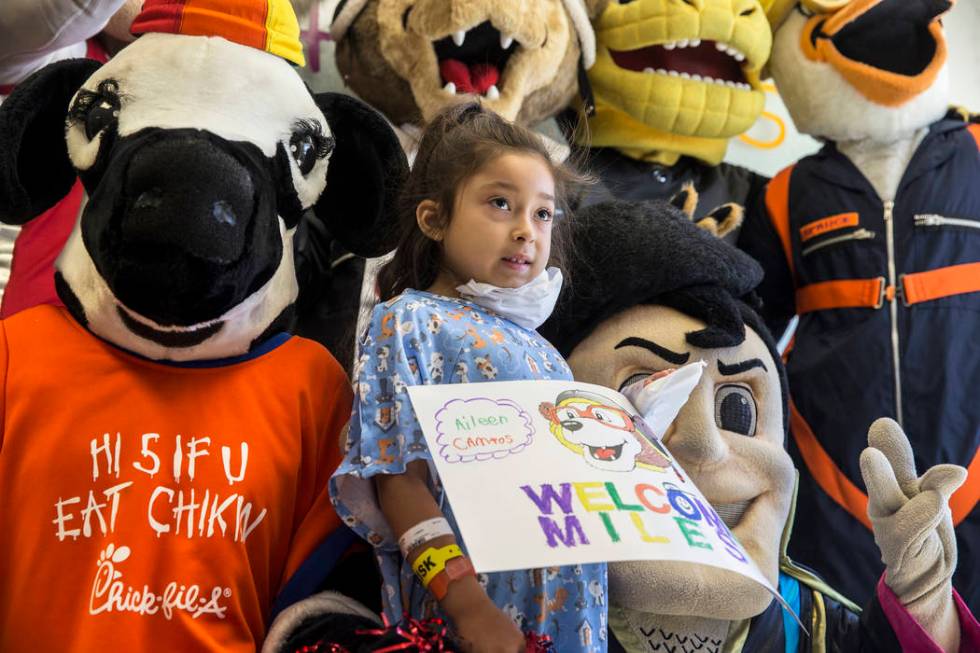 Zaryah Robbs, second from left, 8, takes a photo with the Chick-fil-A Cow, left, and the LV Lig ...
