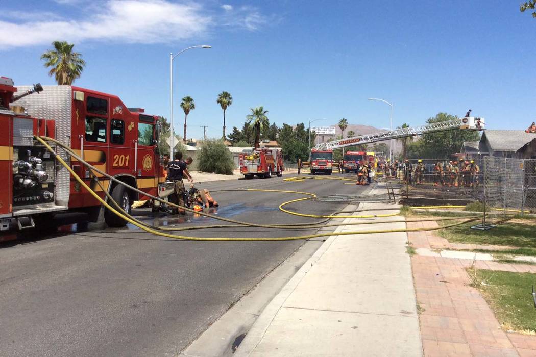 Las Vegas firefighters work a fire that started in one house and spread to two others in the 21 ...
