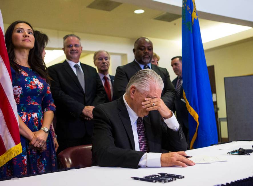 Gov. Steve Sisolak pauses for a moment before signing a trio of bills, including AB291, which i ...