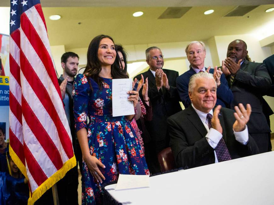 Gov. Steve Sisolak, right, claps after signing bill AB291, which includes a variety of gun cont ...