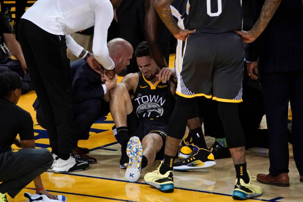 Golden State Warriors guard Klay Thompson, center, is helped up after being injured during the ...