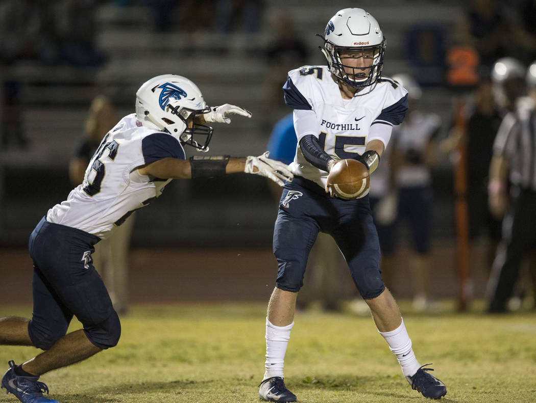 Foothill quarterback Koy Riggin (15) hands off the ball to running back Mario Armendariz (26) a ...