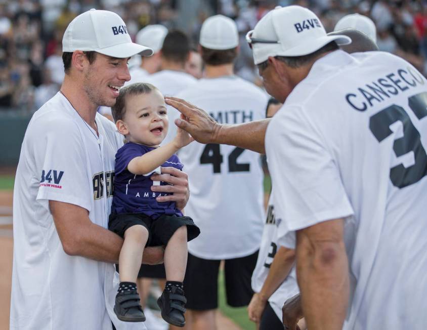 Golden Knights right wing Reilly Smith, left, holds Jordan Rey, 2, as he gets a high five from ...