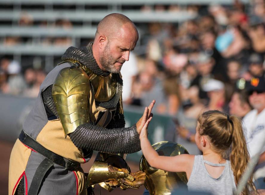 Lee Orchard, aka The Golden Knight, left, high fives a fan during the Battle For Vegas Charity ...