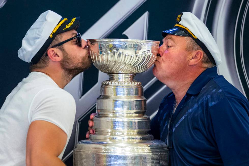 Fans Christian St. Pierre and his father Guy of Ottawa, Canada, kiss the Stanley Cup, the most ...