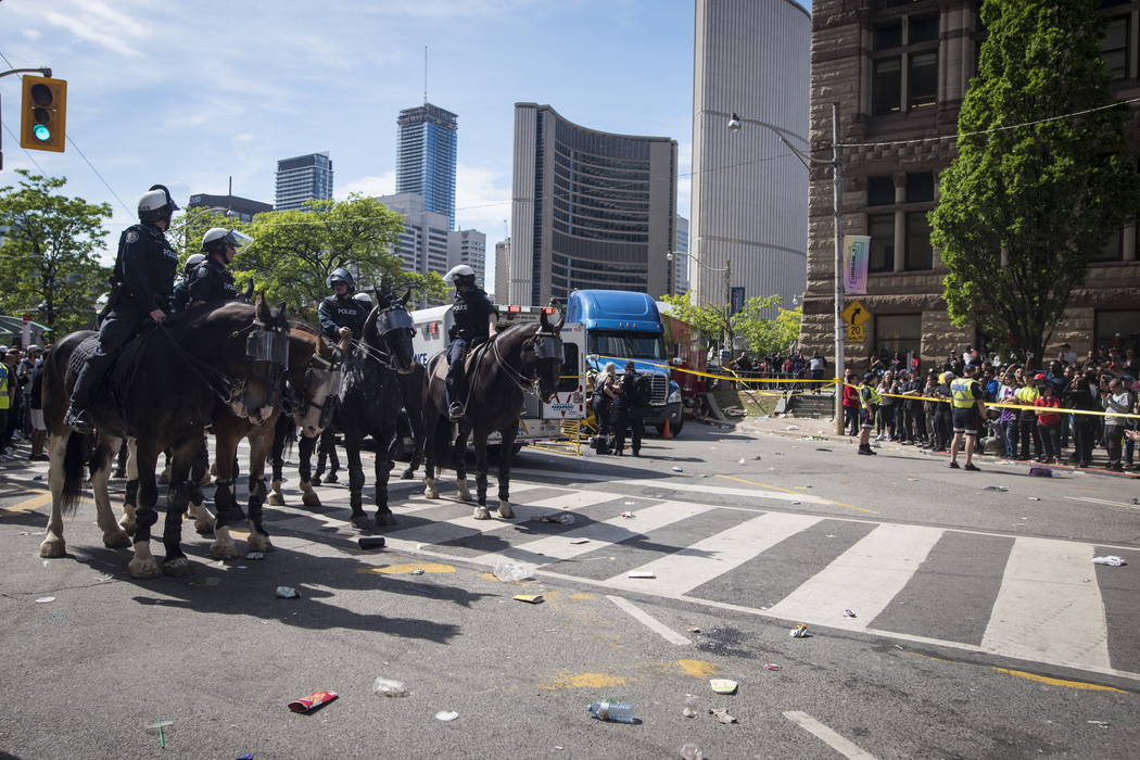 Police block the street as first responders attend to an injured person after shots were fired ...