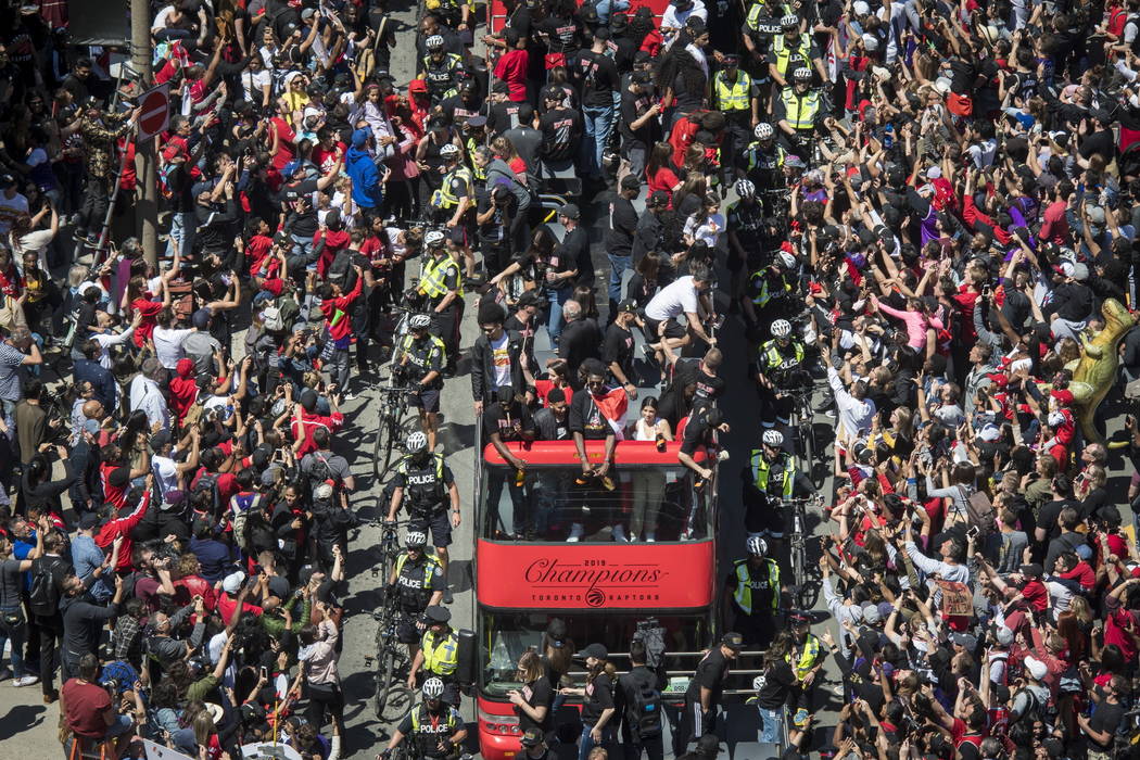 Members of the Toronto Raptors NBA basketball championship team ride on a bus during a victory ...