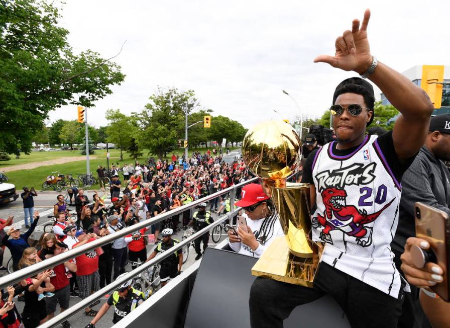 Toronto Raptors guard Kyle Lowry waves to fans while holding the Larry O'Brien Championship Tro ...