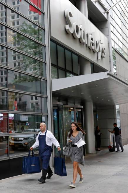 A Sotheby's worker carries bags outside the auction house, in New York, Monday, June 17, 2019. ...