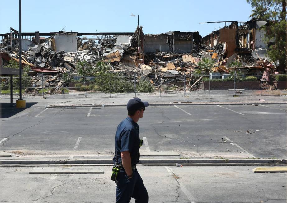 A Clark County firefighter walks past the rubble of burned-out office building at The Park at 3 ...