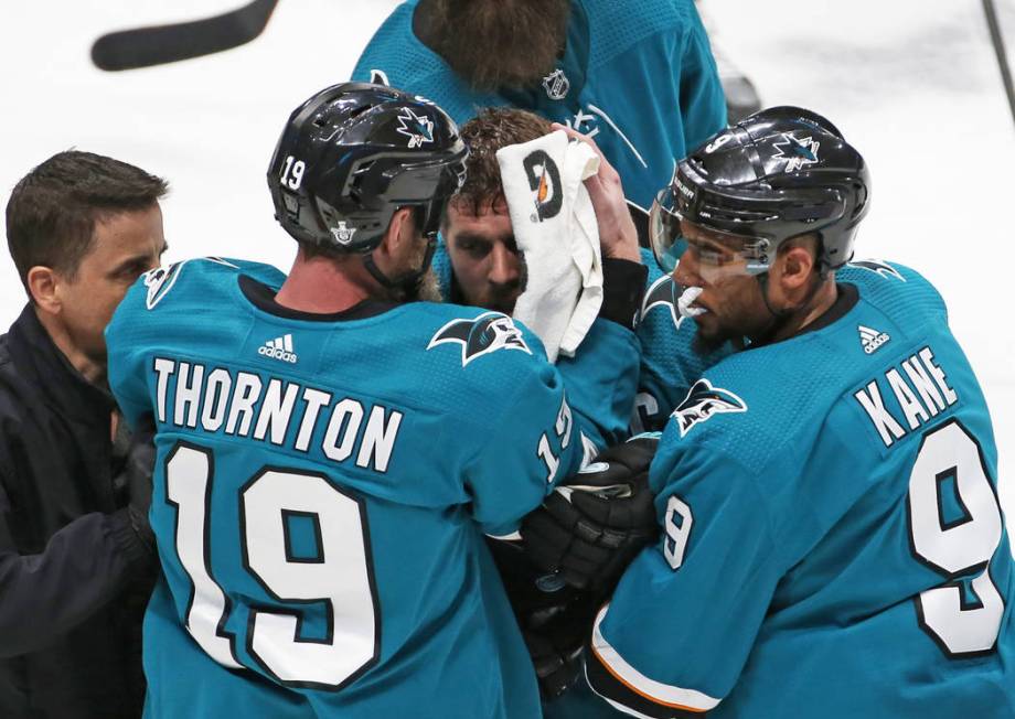 Sharks center Joe Pavelski, middle, is helped off the ice by Sharks left wing Evander Kane (9) ...