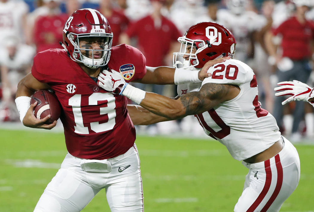 Alabama quarterback Tua Tagovailoa (13) fights off Oklahoma safety Robert Barnes (20), during t ...