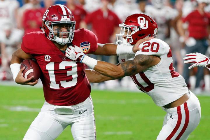 Alabama quarterback Tua Tagovailoa (13) fights off Oklahoma safety Robert Barnes (20), during t ...