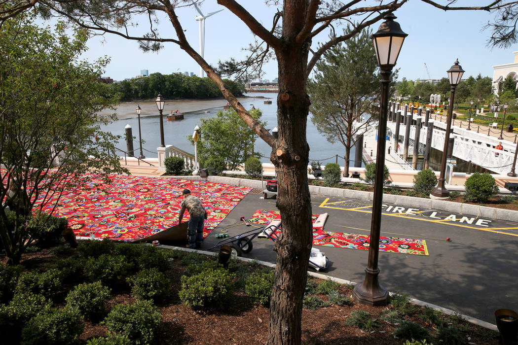 Workers cut carpet in front of the Mystic River as seen from the porte-cochere at Encore Boston ...