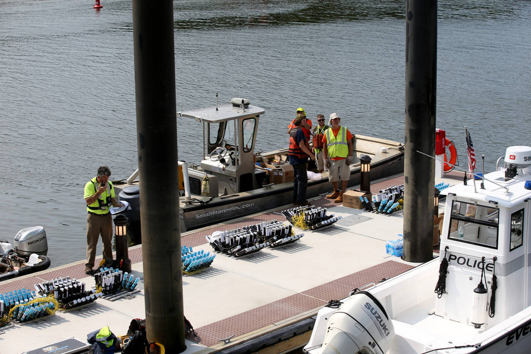 Workers prepare to move fireworks to barges on the Mystic River at Encore Boston Harbor in Ever ...