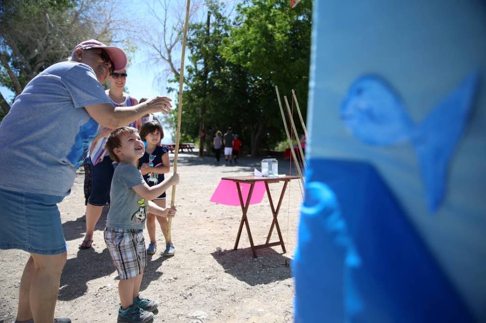 Volunteer Marcella Booth, left, helps Jackson Sharpe, 3, with a fishing game, as his mother Dan ...