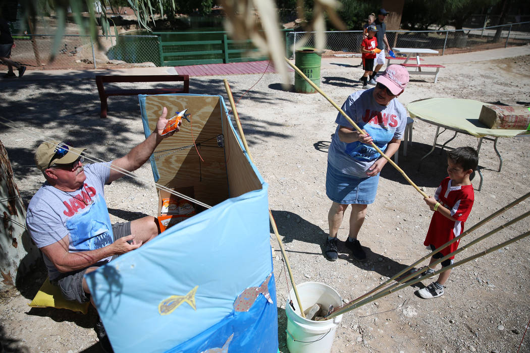 Volunteers Richard Booth, from left, and his wife Marcella, assist Evan Albidrez, 5, of Las Veg ...