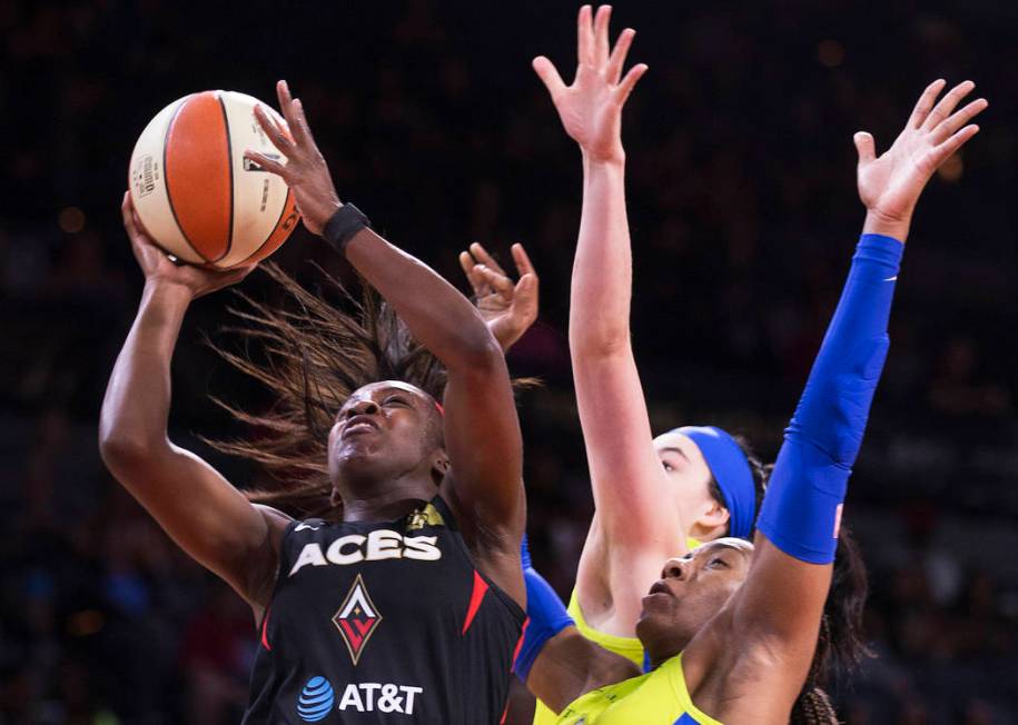 Las Vegas Aces guard Jackie Young (0) drives past Dallas Wings guard Allisha Gray (15) and Dall ...