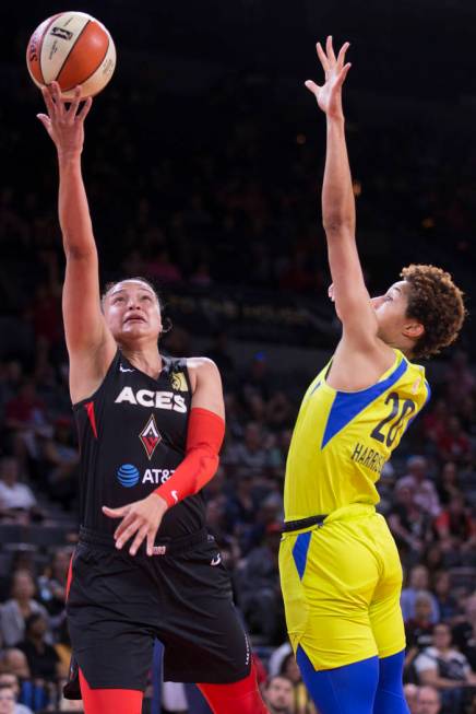 Las Vegas Aces guard Kayla McBride (21) drives past Dallas Wings forward Isabelle Harrison (20) ...