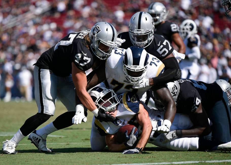 Los Angeles Rams running back Nick Holley runs the ball defended by Oakland Raiders linebacker ...