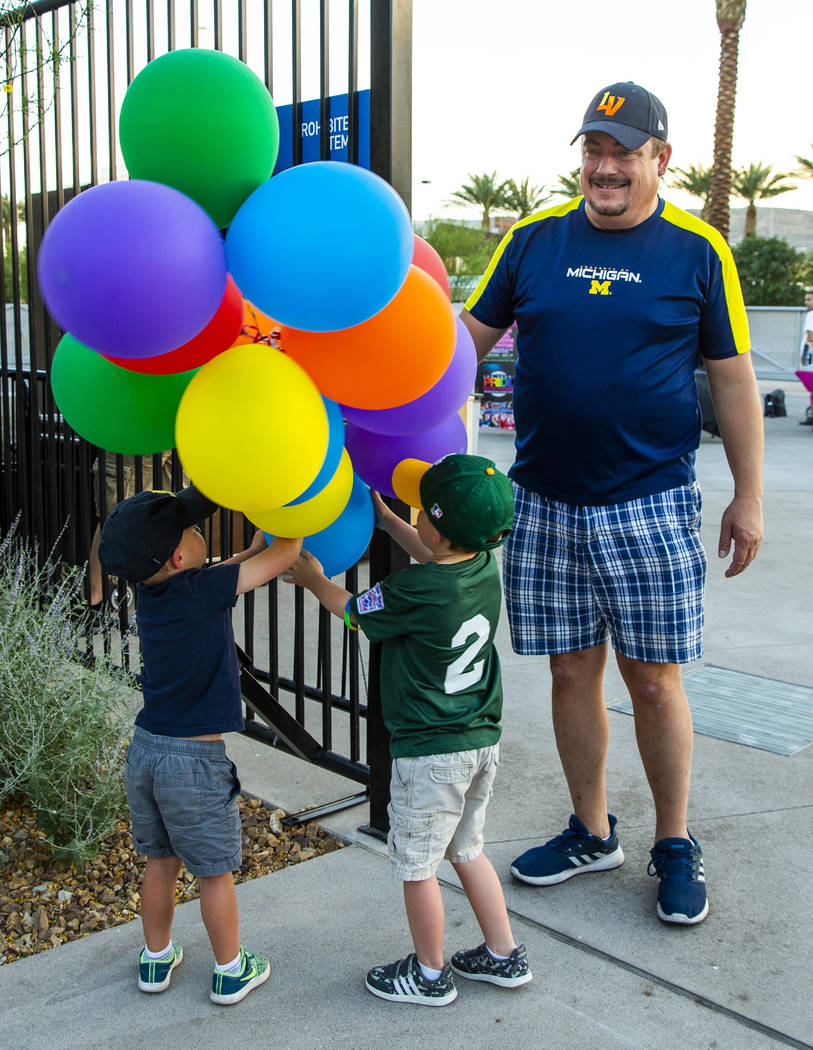 Anthony Allen, 3, and Donald Allen, 4, play with colored balloons as Kevin Lecik looks on about ...