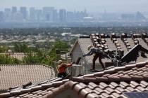 Construction workers set bundles of tile on the roof of an under-construction house in Summerli ...