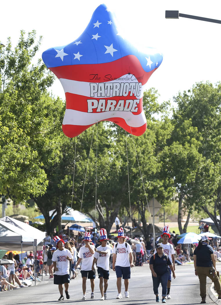 Participants walk with a patriotic star balloon to start the Summerlin Council Patriotic Parade ...