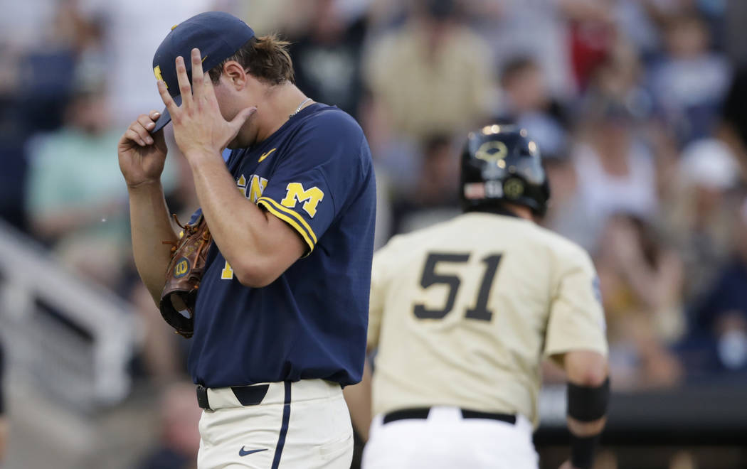 Michigan pitcher Jeff Criswell, left, adjusts his cap as he walks to the dugout after the fourt ...