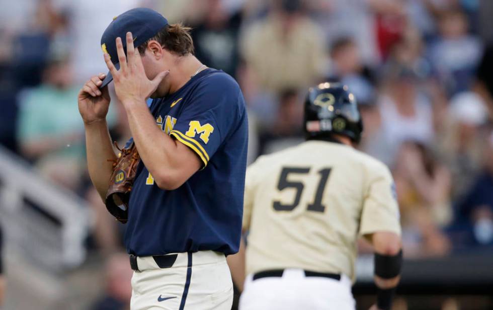 Michigan pitcher Jeff Criswell, left, adjusts his cap as he walks to the dugout after the fourt ...