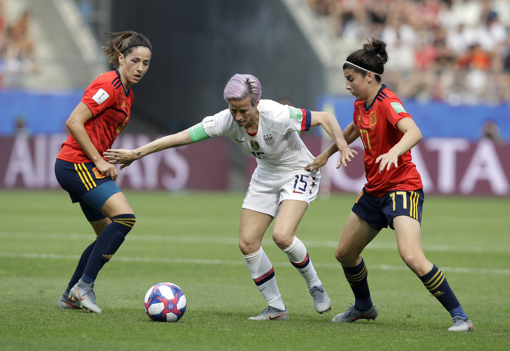 United States' Megan Rapinoe, middle, is challenged by Spain's Vicky Losada, left, and her team ...