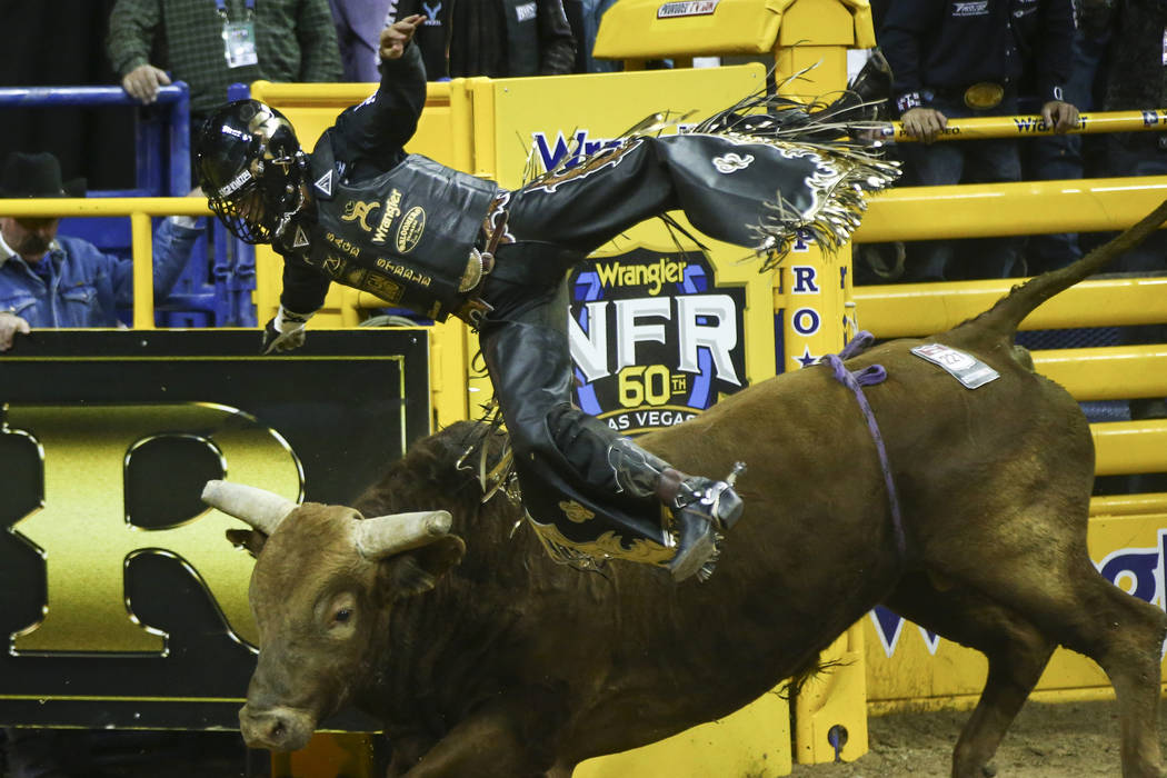 Sage Kimzey of Strong City, Okla. gets upended by "Mortimer" after completing his bul ...