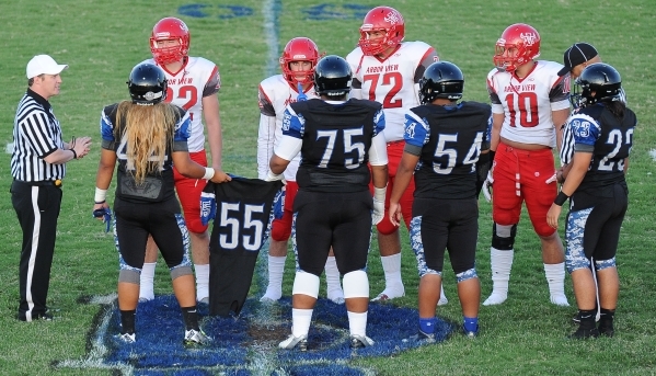 Desert Pines captains carry the No. 55 jersey of injured senior defensive end Anthony Smith ...