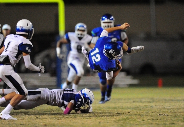 Green Valley Gators quarterback A.J. Amelburu is tripped up by Basic Wolves safety Jake Wald ...